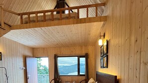 Une chambre dans une cabane en bois, avec un lit, un bureau et une fenêtre donnant sur un paysage agréable.