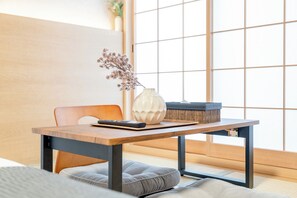 A traditional Japanese room with tatami flooring, a low wooden table, a white vase with dried flowers, a black remote control, and a woven basket. - b&Tengachaya3 (Osaka)
