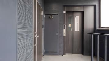 Un couloir moderne avec une porte fermée, une petite fenêtre et une rambarde en métal.
