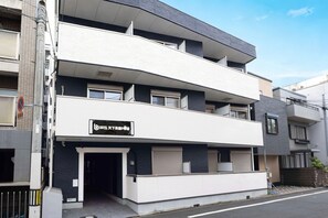 A multi-story building with a flat facade, large windows, and a sign indicating a business or service on the ground floor. - b&Tengachaya3 (Osaka)
