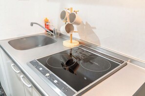 A kitchen with a double sink, a stove with a control panel, and a wooden mug rack.