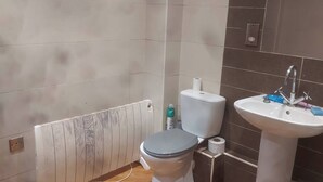 A bathroom with a toilet, sink, and radiator.