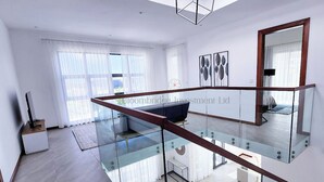 Un appartement moderne doté d’un escalier en verre, d’un coin repas et d’un salon avec une grande fenêtre.