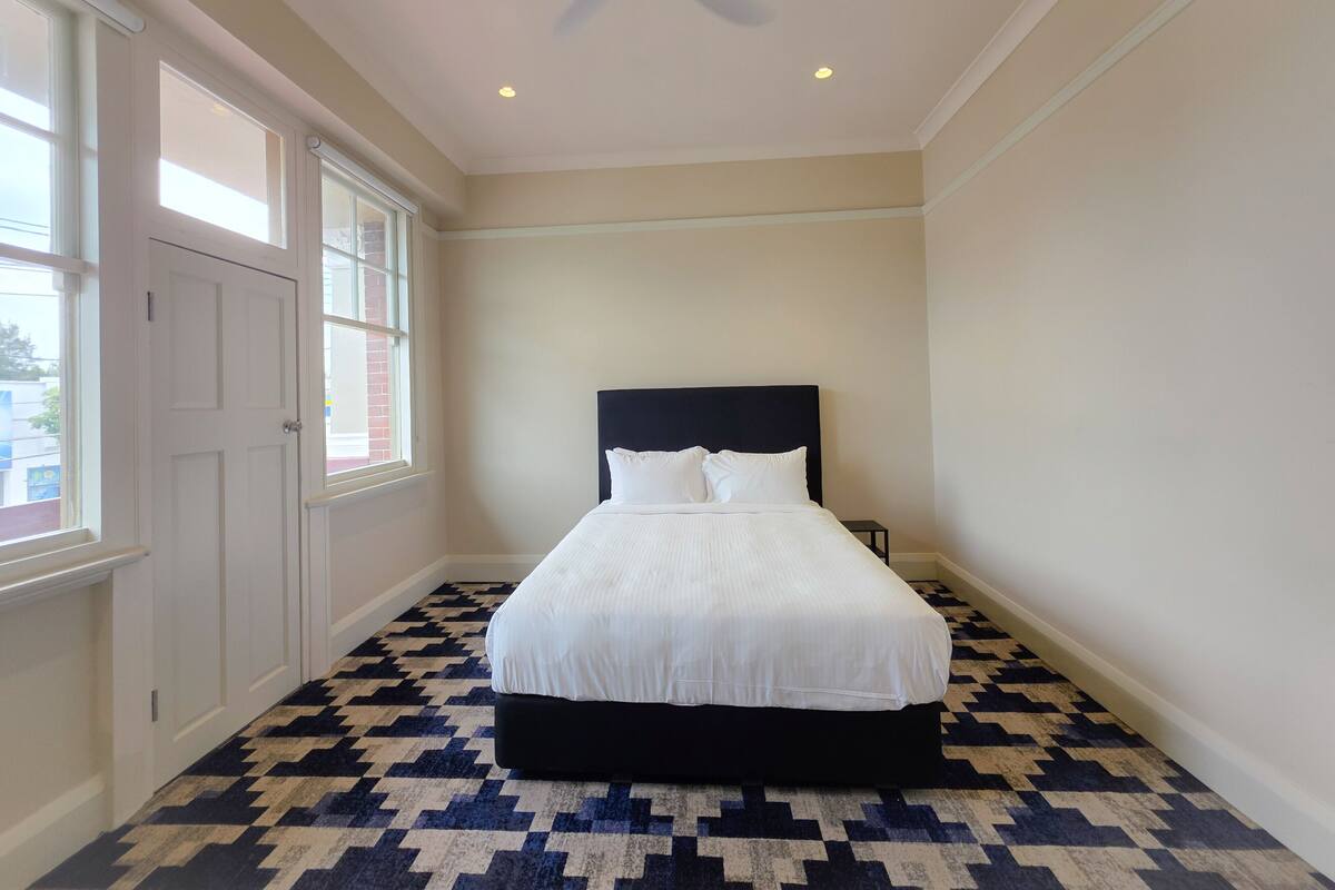 A bedroom with a bed, a ceiling fan, and a patterned floor.
