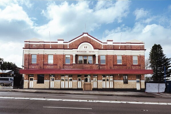 Hotel Riverview de dos pisos, con fachada de ladrillo clásico, ventanas grandes y una entrada destacada.