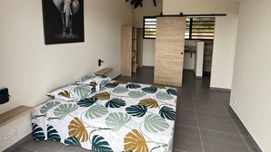 Une chambre à coucher avec un lit, un tableau représentant un éléphant et une vue sur un couloir.