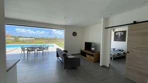 Un salon moderne avec vue sur la piscine, comprenant un canapé, un téléviseur et un lit.