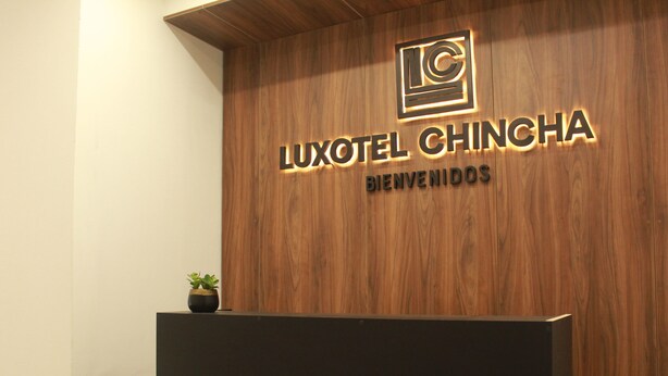 Un mostrador de recepción de madera con un cartel que dice "LUXOTEL CHINCHA BIENVENIDOS".