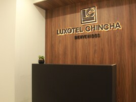 Un mostrador de recepción de madera con un cartel que dice "LUXOTEL CHINCHA BIENVENIDOS".