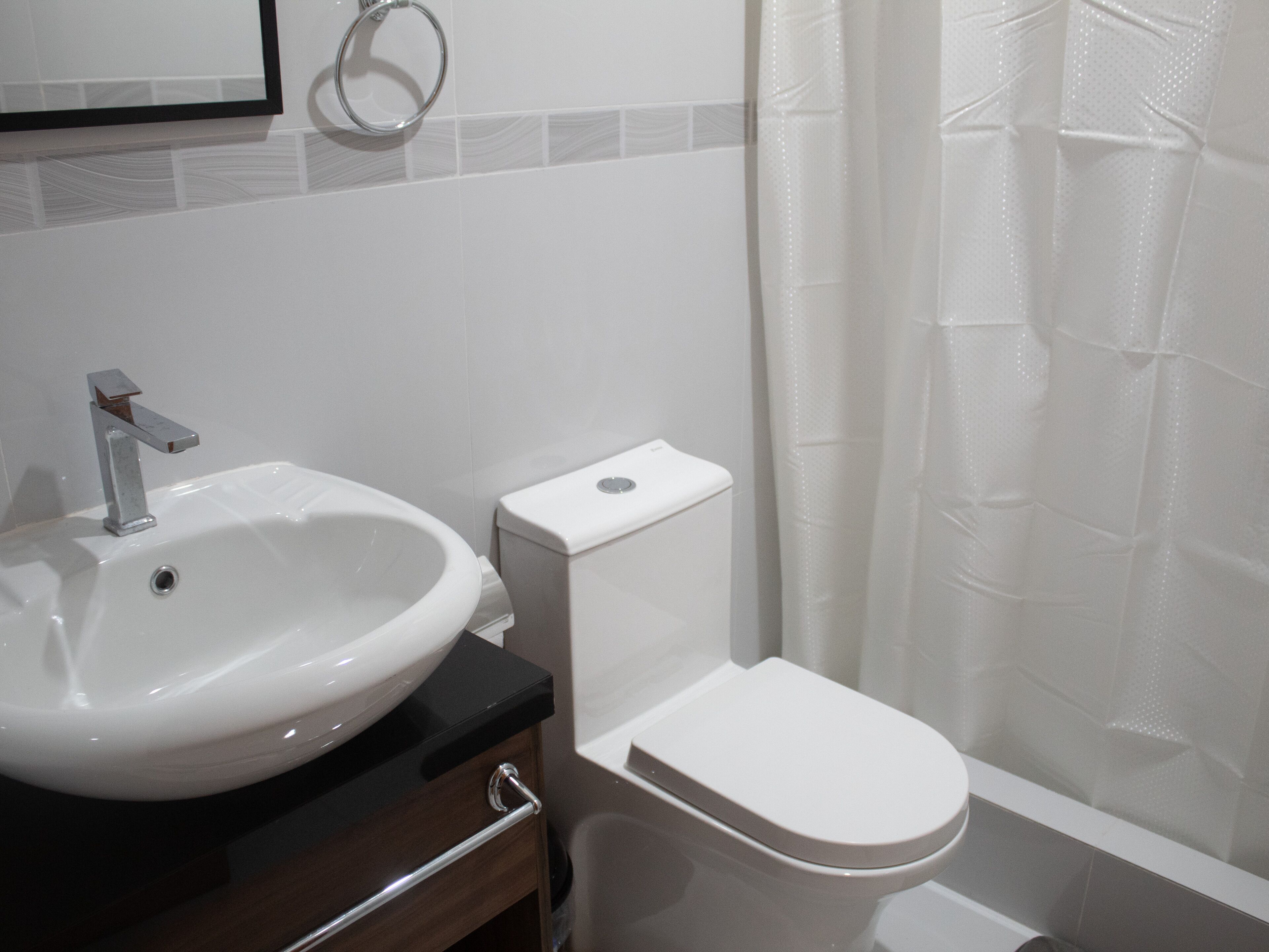A bathroom with a white sink, a toilet, and a shower curtain.