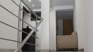 Una escalera con barandales metálicos y escalones de madera que conduce a una habitación con un sillón color beige.