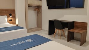 Una habitación de hotel con una cama, un escritorio y un televisor.