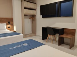 Una habitación de hotel con una cama, un escritorio y un televisor.