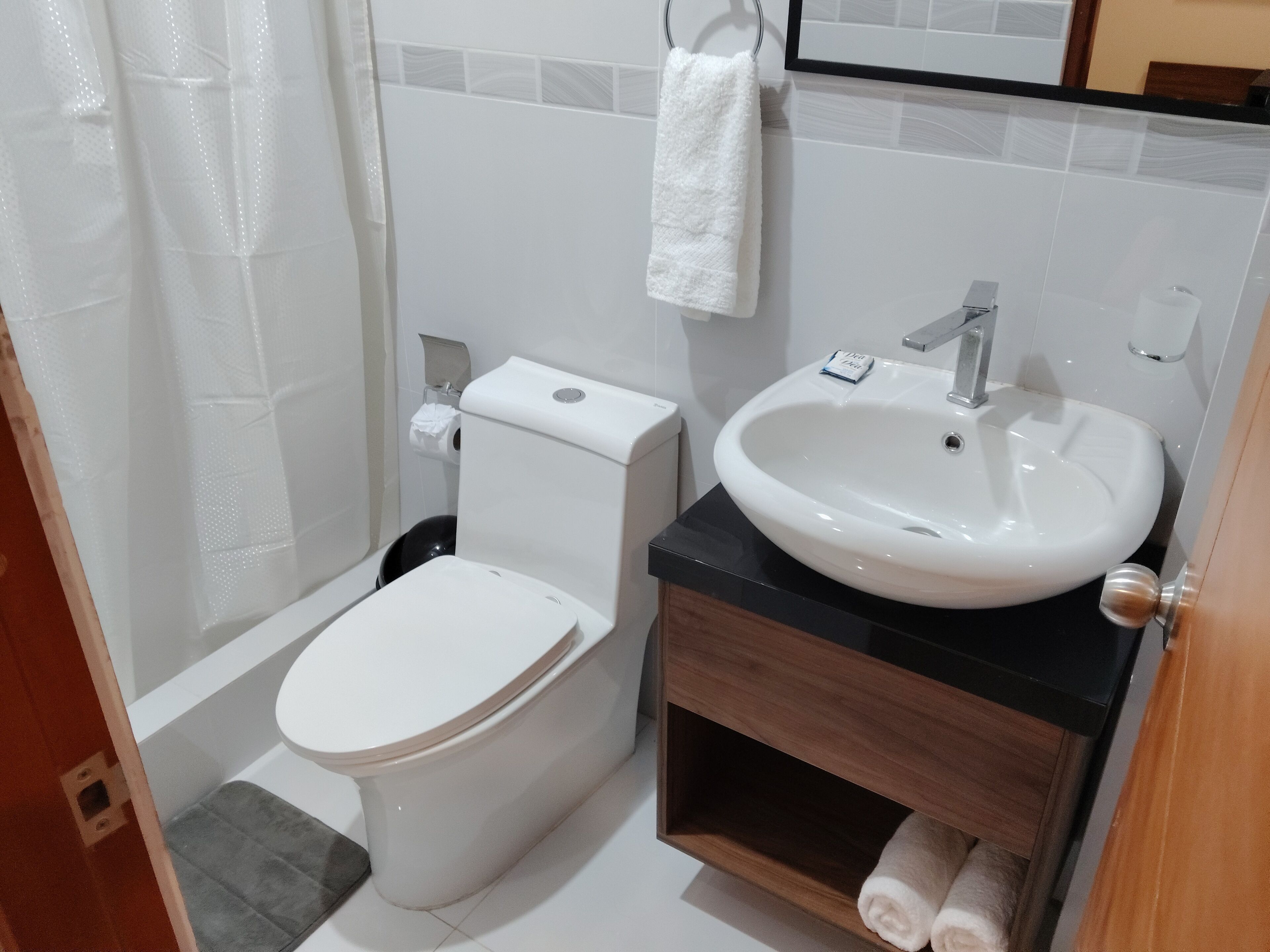 A small bathroom with a toilet, sink, and a towel hanging on the wall.