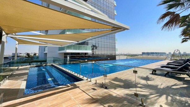 Ein Poolbereich auf dem Dach mit Glasgeländer, einem Pool und Liegestühlen.