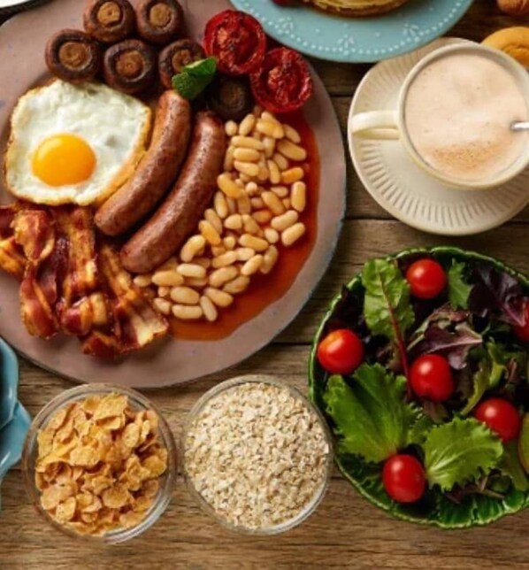 Un plato de desayuno con huevos, salchichas, frijoles y tocino.
