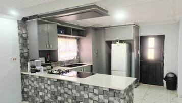 A modern kitchen with grey cabinets, a built-in island, and a stone backsplash.