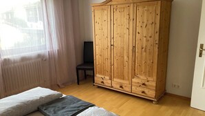 A bedroom with a wooden wardrobe, a bed with pillows, and a chair. - Vacation apartment in Starnberg, close to the lake and town (Starnberg)