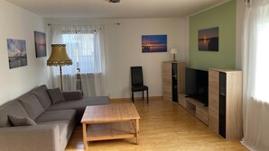 A living room with a sofa, a wooden coffee table, a TV stand, and a lamp. - Vacation apartment in Starnberg, close to the lake and town (Starnberg)