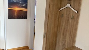 A room with a wooden wardrobe, a small table, and a wall-mounted picture of a sunset over water. - Vacation apartment in Starnberg, close to the lake and town (Starnberg)