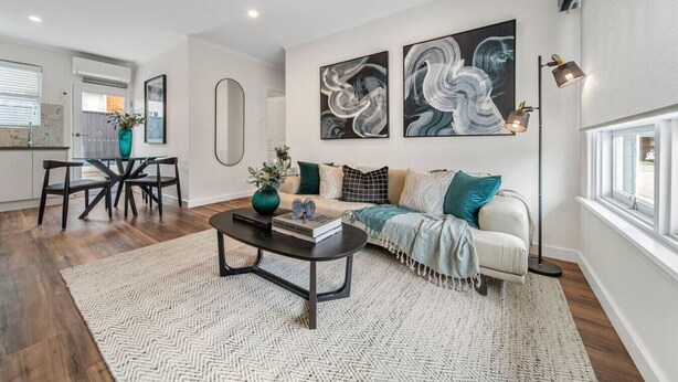 Una sala de estar moderna con sofá, mesa de centro y una obra de arte en la pared.
