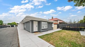 A single-story house with a covered porch, a red roof, and a fenced backyard. - One Tea House—Contemporary Cityside Comfort (Mile End)