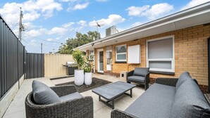 A patio with wicker furniture, a barbecue grill, and potted plants. - One Tea House—Contemporary Cityside Comfort (Mile End)