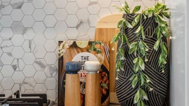 A kitchen with a hexagonal tile backsplash, wooden spice jars, and a potted plant. - One Tea House—Contemporary Cityside Comfort (Mile End)