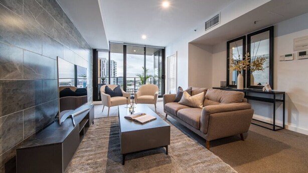 Una sala de estar moderna con un sofá, sillones, una mesa de centro y un televisor.