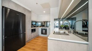 Une cuisine moderne avec un réfrigérateur noir, des armoires blanches et un plancher en bois.