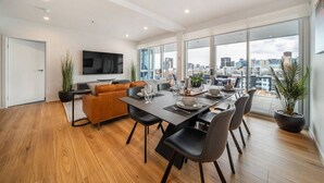 Un salon moderne avec un coin repas, de grandes fenêtres et une vue sur la ville.