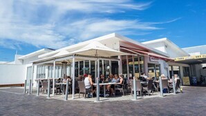 An outdoor seating area with tables and chairs under a white canopy, in front of a building with a sign that reads "DRY CLEAN THRU." - Salt at Arlo`s - Cosy Comfort near Glenelg Beach (Glenelg South)