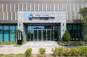 Un edificio moderno con entrada de vidrio, un letrero que dice 'Best Western Asan' y una rampa accesible para sillas de ruedas.