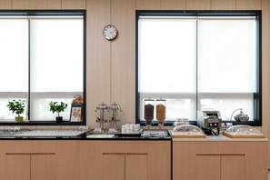 Ein Frühstücksbuffet mit einer Uhr, zwei Blumentöpfen und einer Kaffeemaschine.