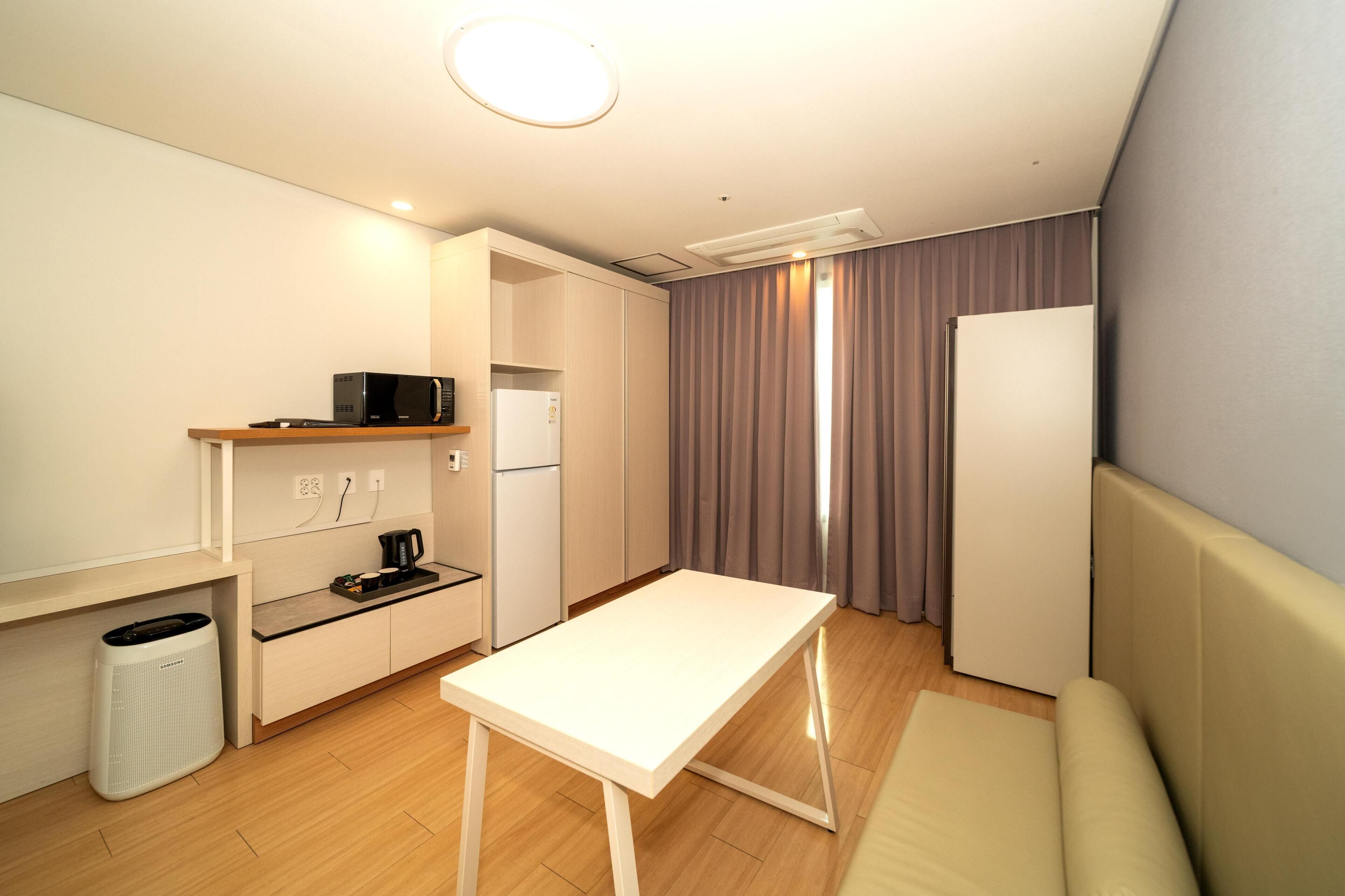 Una kitchenette compacta con microondas, cafetera y refrigerador pequeño.