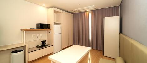 Una kitchenette compacta con microondas, cafetera y refrigerador pequeño.