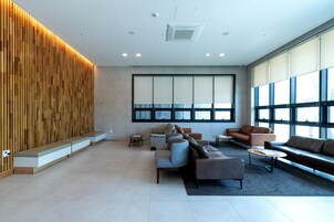 Un vestíbulo moderno con asientos, ventanas amplias y una pared decorativa de madera.