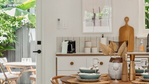 Un coin repas avec une table ronde en bois, des chaises en osier et un luminaire suspendu.
