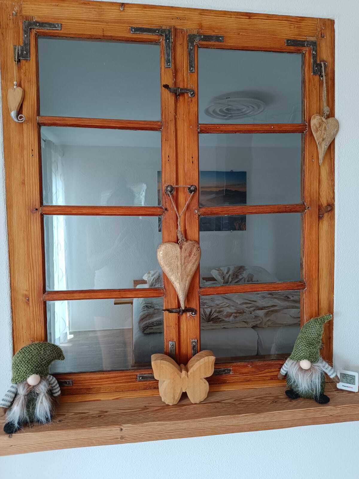 Puerta doble de madera con paneles de vidrio, un adorno con forma de corazón y dos figuras de gnomos en un estante.