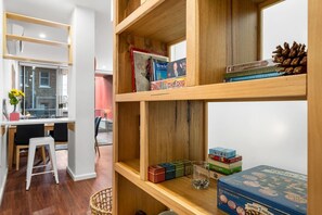 A room with a dining area, a bookshelf with board games, and a window with a view. - Tropicana on Bent—A Walkable Adelaide CBD Base (Adelaide)