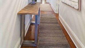 A hallway with a wooden bench, a hanging light fixture, and a patterned rug. - Blackbird at Arlo`s—Heritage meets Designer Charm (Glenelg South)