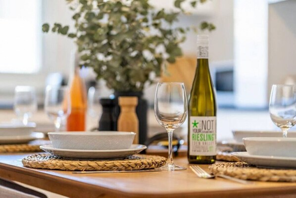 A dining table set with plates, a wine bottle, and glasses. - Kairos in Keswick—Character-filled Escape near CBD (Keswick)