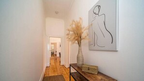 A hallway with wooden flooring, a bench, a vase with pampas grass, and a framed line drawing on the wall. - Kairos in Keswick—Character-filled Escape near CBD (Keswick)