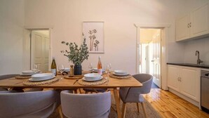 A dining area with a wooden table set for four, surrounded by grey chairs. There is a potted plant on the table, and a framed artwork hangs on the wall above. - Kairos in Keswick—Character-filled Escape near CBD (Keswick)