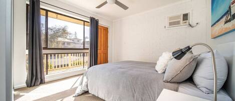 A bedroom with a bed, a ceiling fan, a nightstand, a lamp, and a painting on the wall.