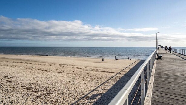 Une plage avec une promenade en bois et des gens qui se promènent.