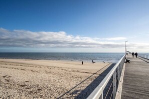 Een strand met een houten vogelzangpad en mensen die wandelen.