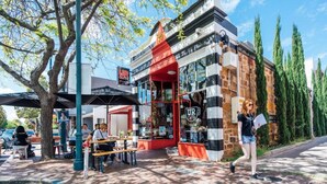 A café with outdoor seating, a red awning, and a brick facade. - In The Midst on Melbourne - Walk to Cafés & Dining (North Adelaide)