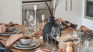 A dining table set with plates, bowls, and wine glasses, with a vase of branches in the center. - In The Midst on Melbourne - Walk to Cafés & Dining (North Adelaide)