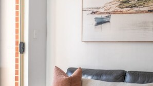 A living room with a leather sofa, a glass coffee table, and a painting on the wall. - In The Midst on Melbourne - Walk to Cafés & Dining (North Adelaide)